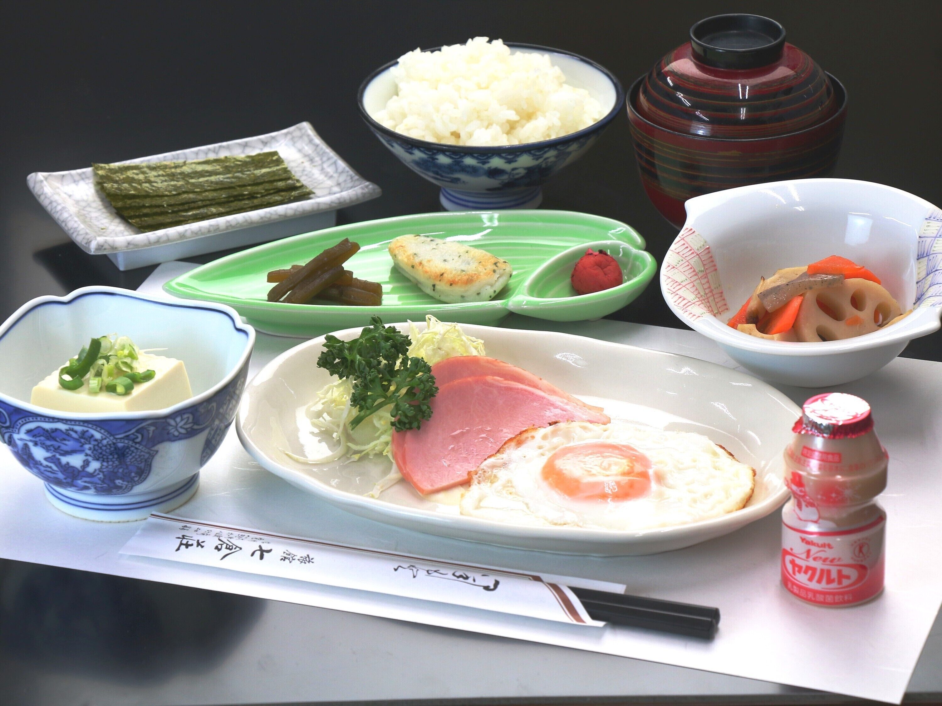 A meal with rice, vegetables, and a piece of meat on a plate.