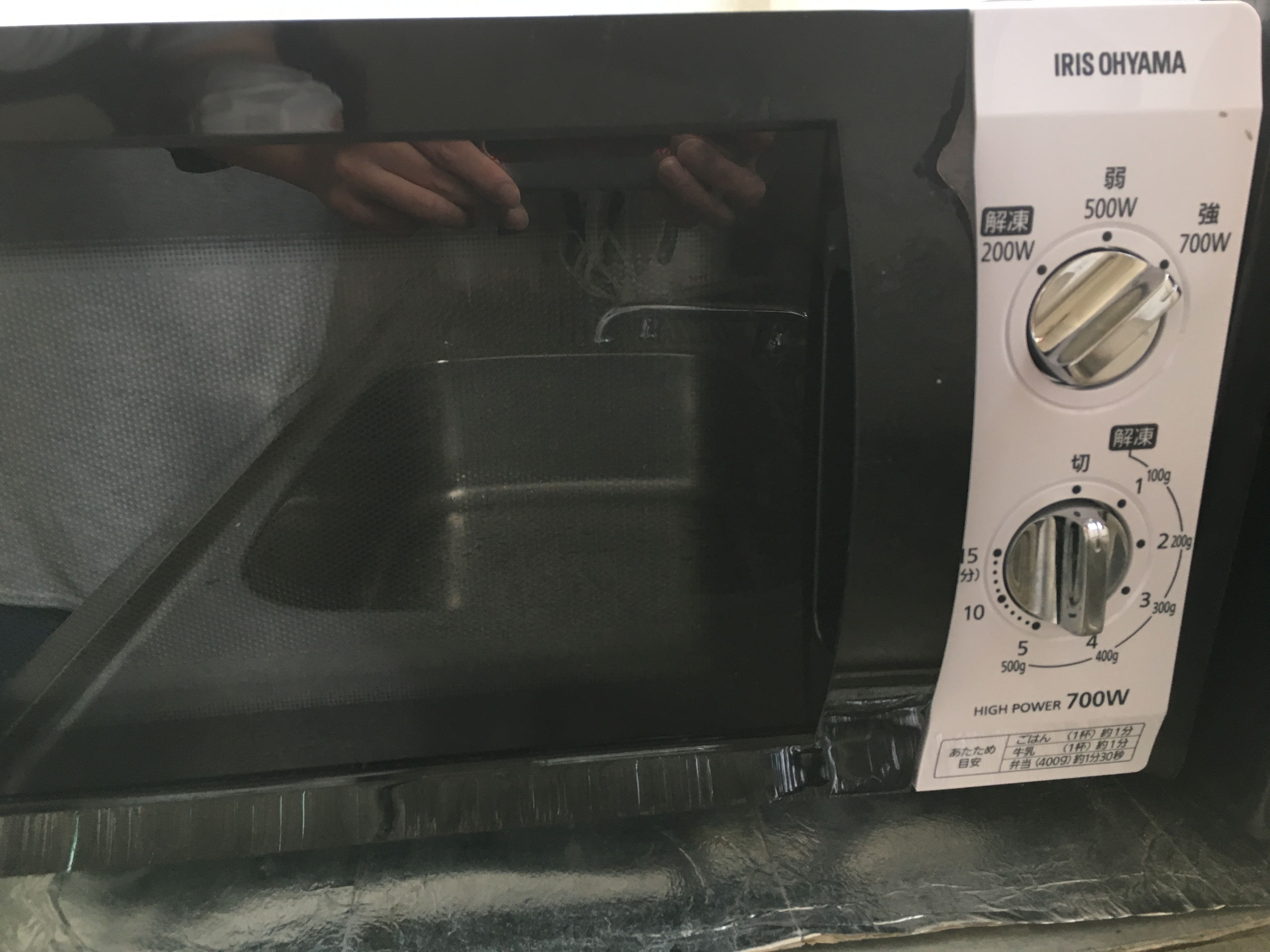 Micro-ondas com porta transparente, configurações de potência e etiqueta indicando alta potência de 700W.