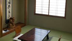 A traditional Japanese room with tatami flooring, a low table, a wooden chair, a calligraphy scroll, and a shoji screen window. - Nanakurasou (Omachi)