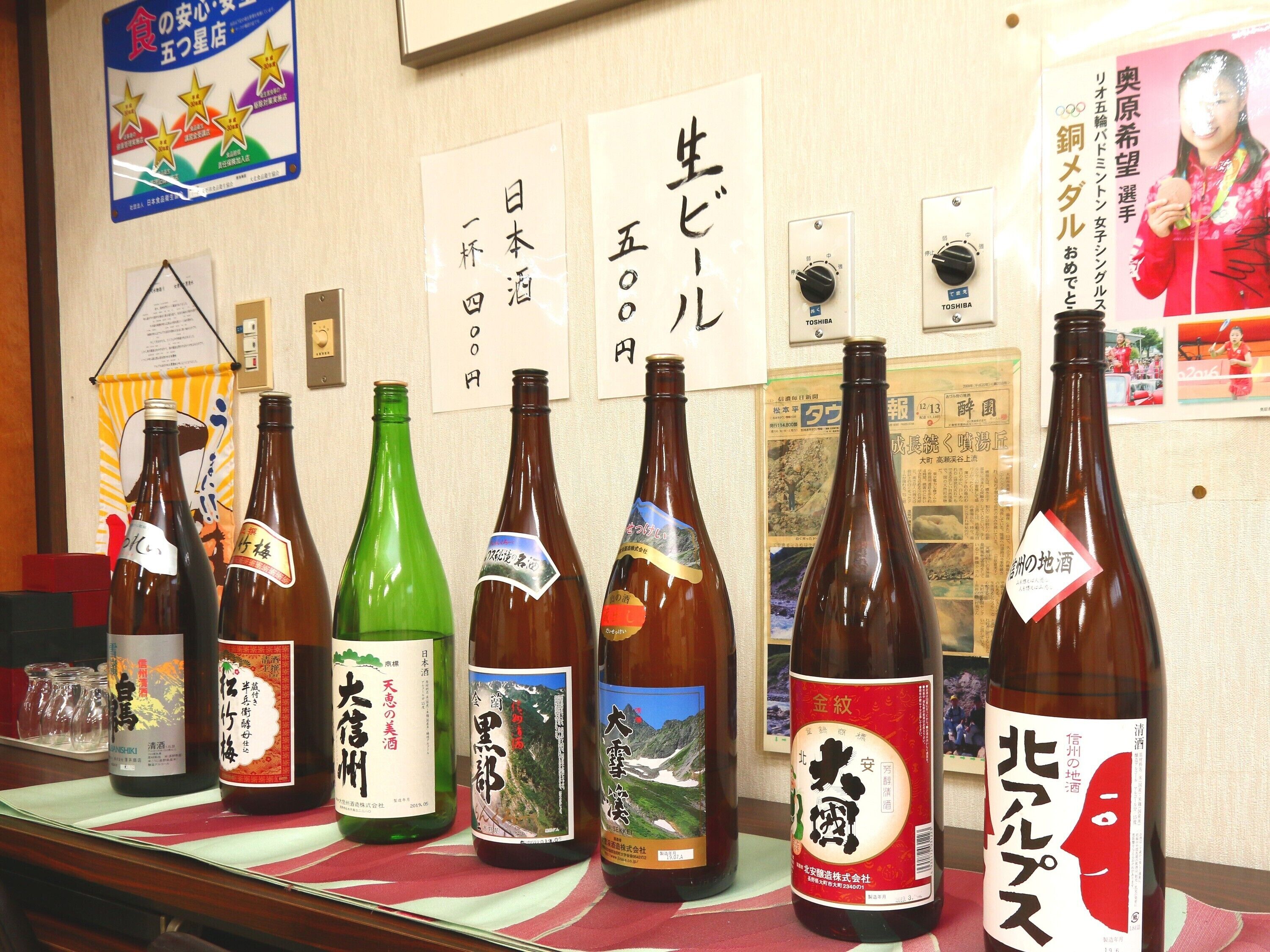 A row of Japanese sake bottles on a counter with various labels and designs.