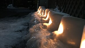 A row of illuminated snow sculptures in front of a building with a sign in a foreign language. - Nanakurasou (Omachi)
