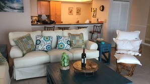Ein Wohnzimmer mit einer Couch, einem Couchtisch und einem Essbereich im Hintergrund.