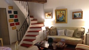 Una sala de estar con escalera, sofá, mesa de centro y lámpara.