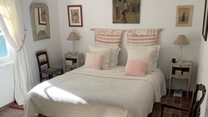 Un dormitorio con una cama grande, dos mesitas de noche, una silla y una alfombra.