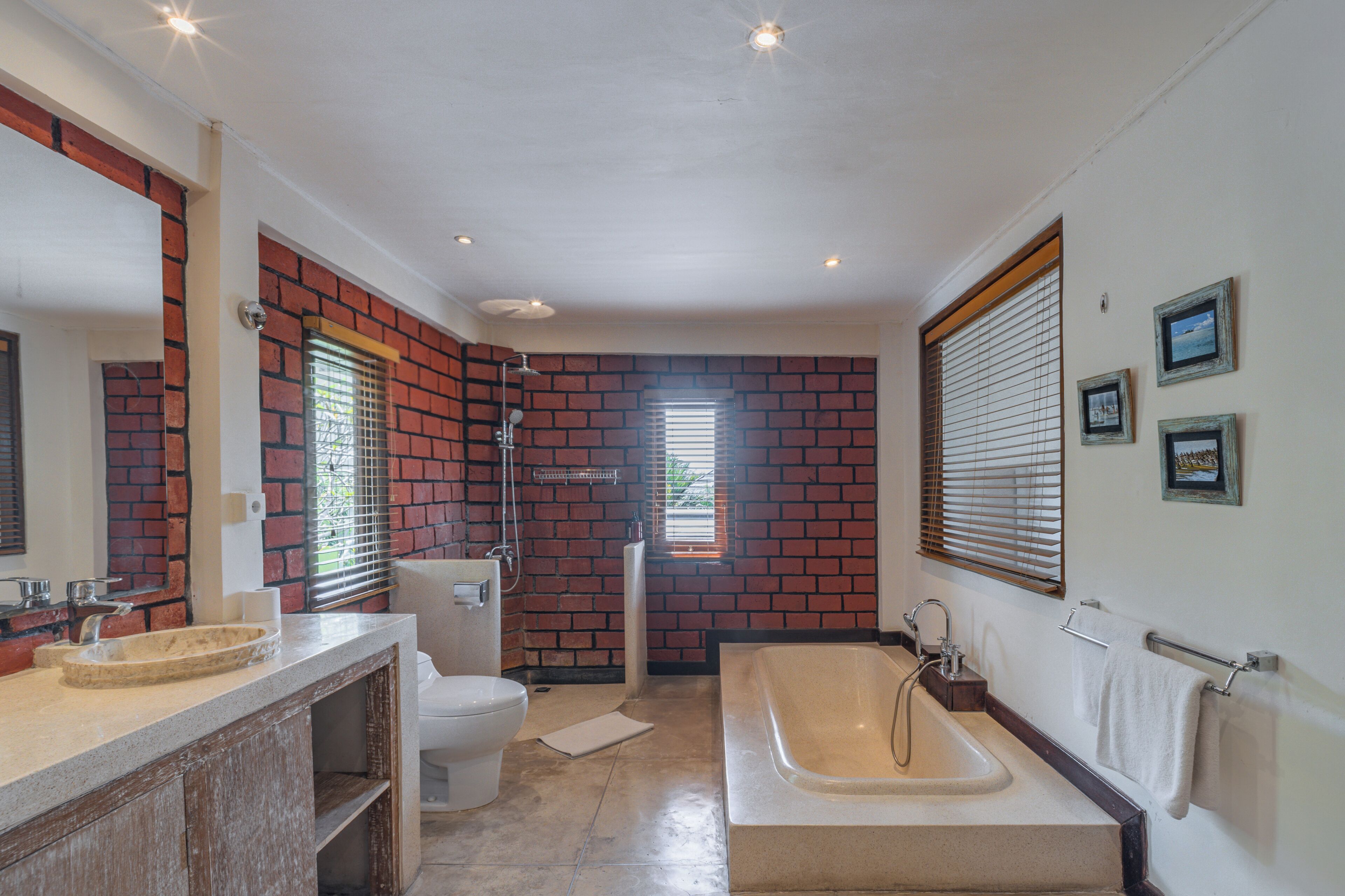 Een badkamer met een bakstenen muur, een bad, een toilet en een wastafel.