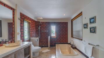 Een badkamer met een bakstenen muur, een bad, een toilet en een wastafel.