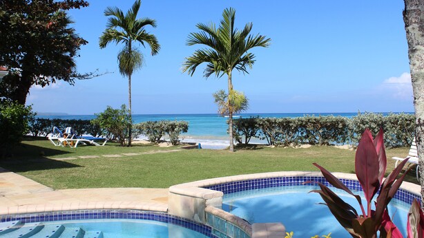 A swimming pool with a view of the ocean, palm trees, and lounge chairs. - Baywatch - seaside villa, modern, spectacular location & garden, pool, cook (Runaway Bay)