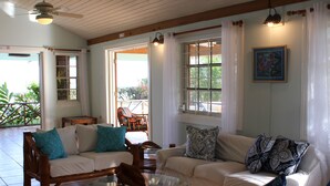 A spacious living area with two sofas, a glass coffee table, and a ceiling fan. - Baywatch - seaside villa, modern, spectacular location & garden, pool, cook (Runaway Bay)