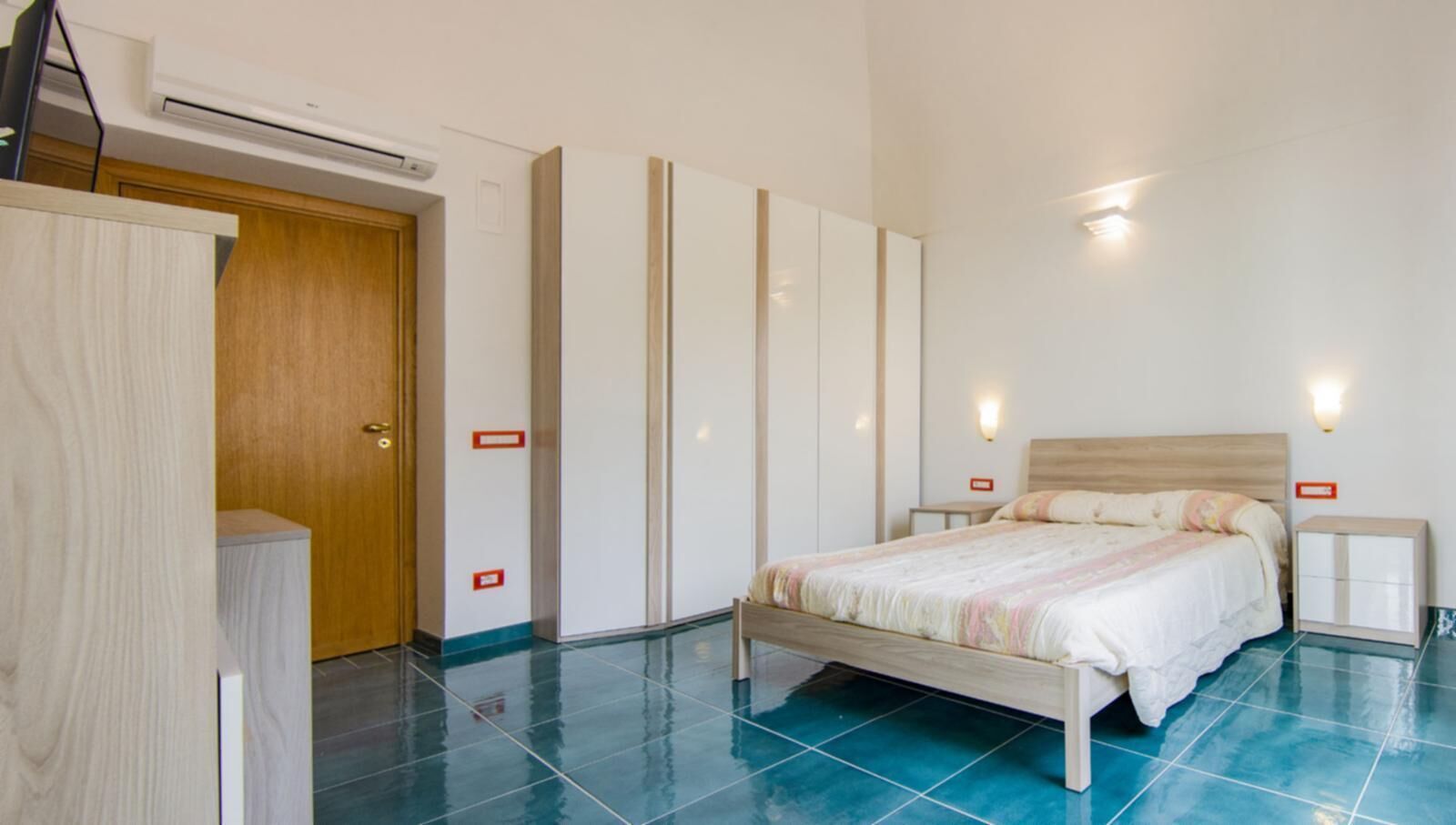 Une chambre à coucher comprenant un lit, des tables de chevet, une armoire et un appareil de climatisation.