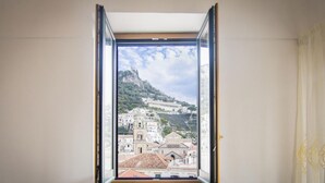 A room with a large window offering a view of a cityscape with historical buildings and a hill.