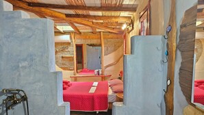 A room with two beds, a wooden ceiling, a stone wall, and a mirror. - Villa Kokkino Skufitza,charming holiday home made of clay, pool, private garden (Pitsidia)