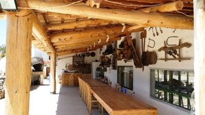 Un intérieur rustique en bois, avec un long banc, des poutres apparentes au plafond et divers ustensiles de cuisine accrochés au mur.