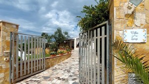 Una entrada cerrada a Villa Luigi, con un muro de piedra y un camino de baldosas.