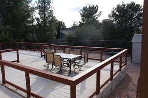 Una terraza de madera con una mesa y sillas, rodeada por una barandilla de metal.