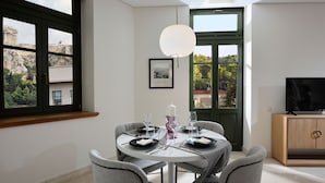 Ein Essbereich mit einem runden Tisch, gedeckt für vier Personen, einem Fernseher auf einer Holzkommode und einem gerahmten Bild an der Wand.