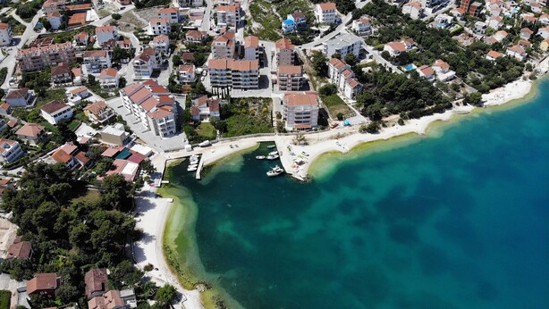 An aerial view of a coastal residential area with buildings, a marina, and a beach. - Apartment Karlo 2 - with Pool, 70m from sea (Okrug Gornji)