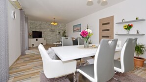 A modern dining area with a white table, grey chairs, and a vase of flowers. - Apartment Karlo 2 - with Pool, 70m from sea (Okrug Gornji)