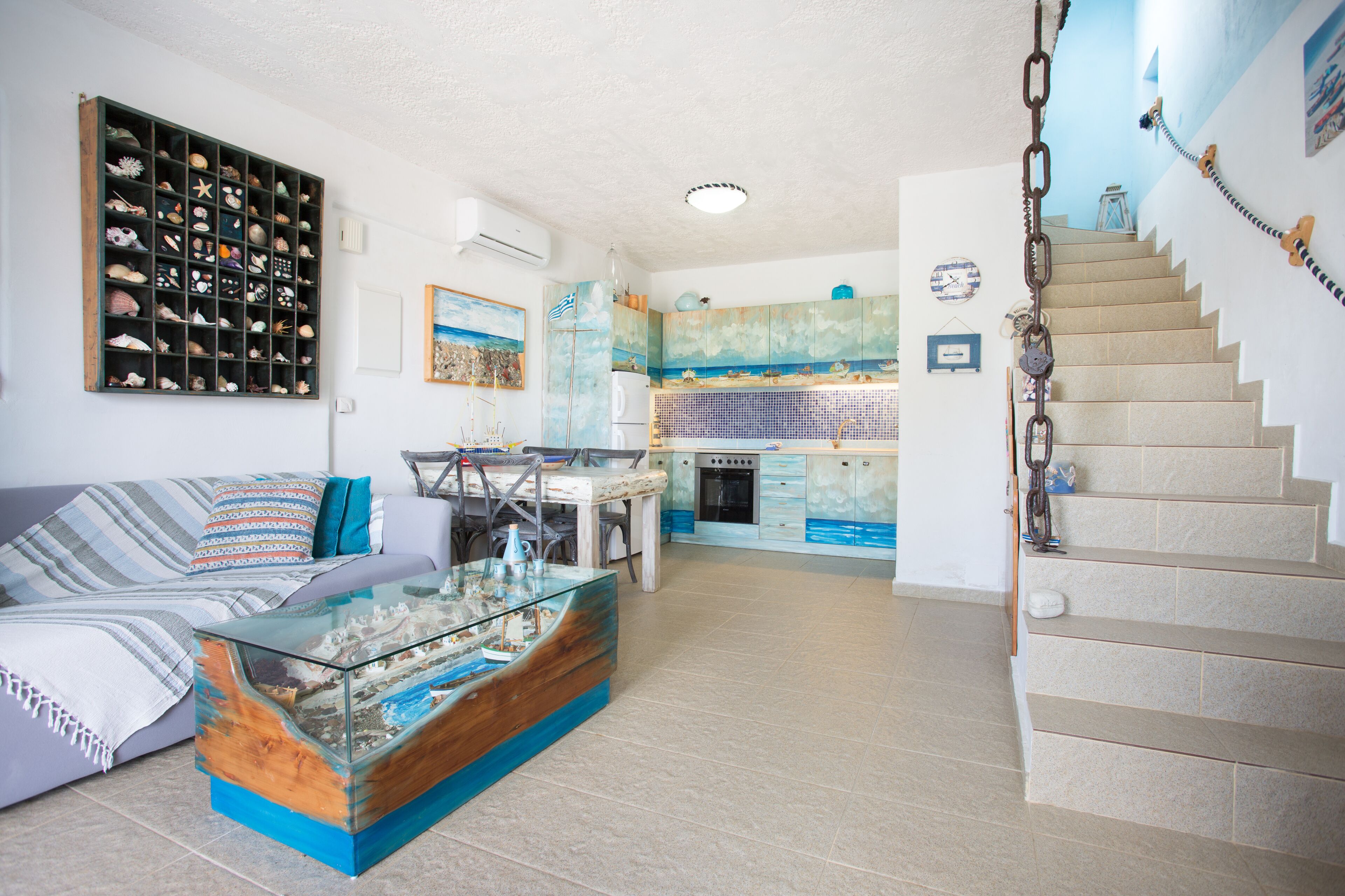 Ein Wohnzimmer mit einer Couch, einem Glastisch, einem an der Wand befestigten Schuhregal und einer Treppe, die in den oberen Stock führt.