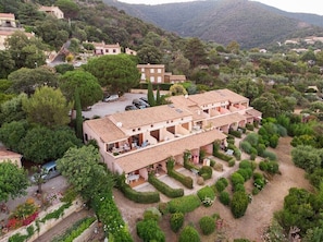 A multi-story hotel with a courtyard, surrounded by lush greenery and hills.
