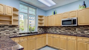 A modern kitchen with beige cabinets, a granite countertop, and a large window providing natural light. - Oceanwalk 2BR with Fountain Views Private Balcony and 5 Min Walk to Beach (New Smyrna Beach)