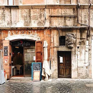 A restaurant with a rustic facade, a wooden door, and a signboard listing menu items. - A Secret Corner: Historic Center, Pantheon, Trevi Fountain, Colosseum, Forum (Roma)