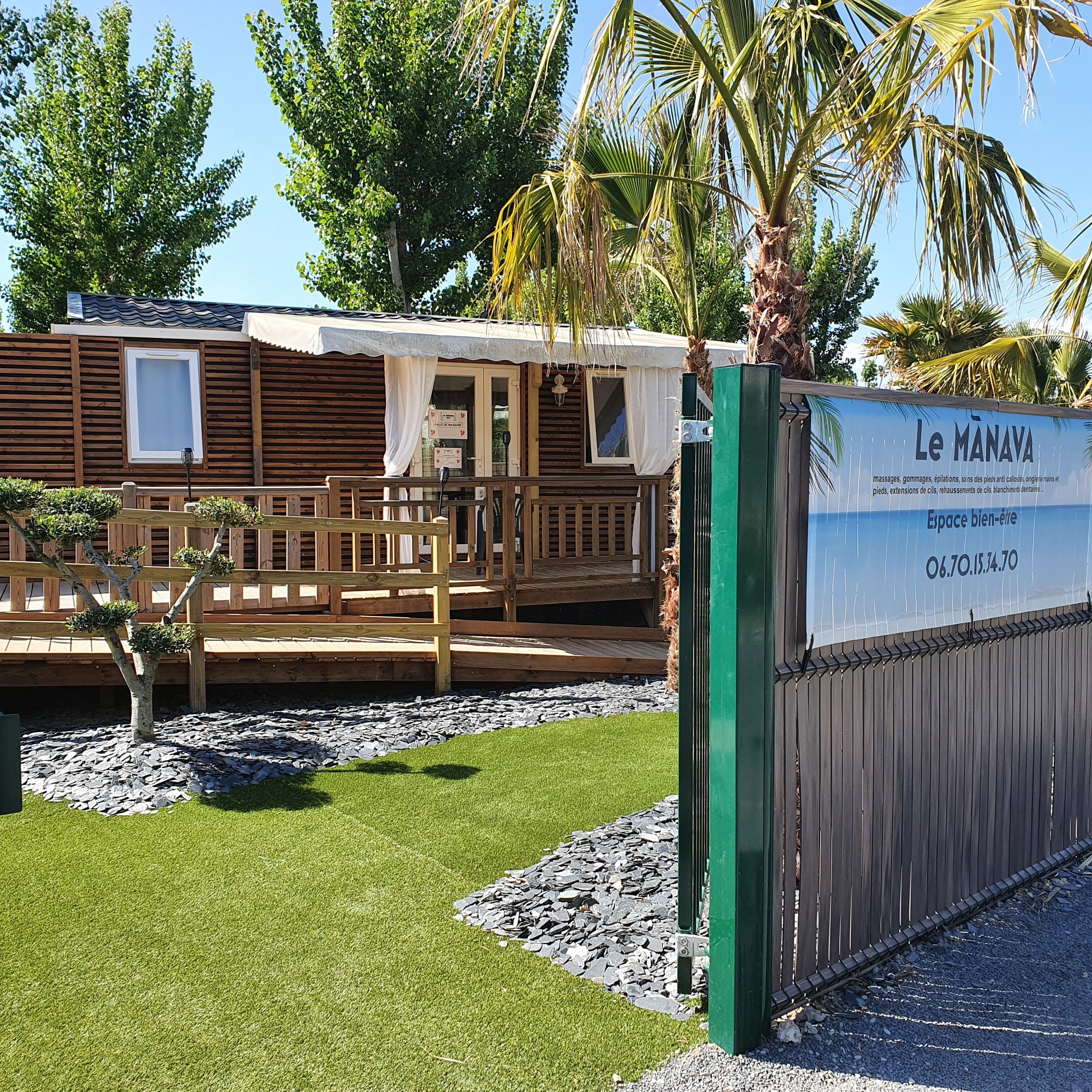 Eine Holzhütte mit überdachter Veranda, einem Schild und einer Palme im Hintergrund.