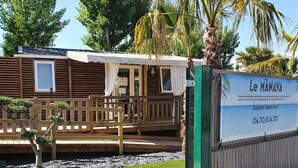 Eine Holzhütte mit einem Schild, das sie als Wellnesszentrum kennzeichnet, mit einer Terrasse und einer kleinen Gartenanlage.