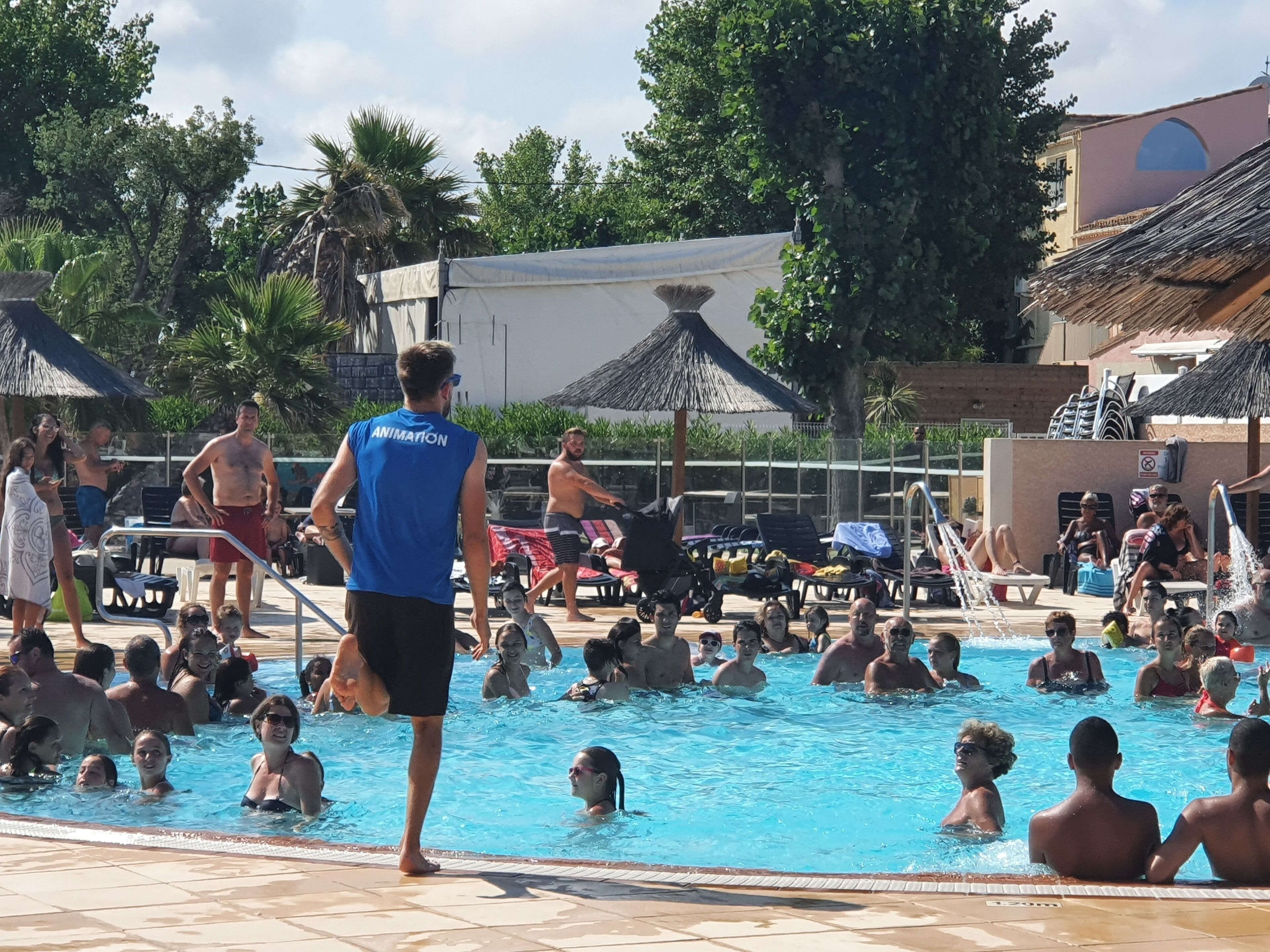 Un espace piscine où des personnes nagent et se détendent au bord de l’eau.