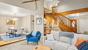 Un salon spacieux avec un escalier en bois, un coin repas et un espace salon confortable.