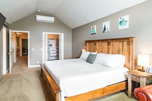 A bedroom with a wooden bed, a nightstand, a lamp, and a closet with a mirror. - Alpine Basecamp: SKI, Hike, Bike, Hot Tub, Game Room, Pets Welcome, near lcc/bcc (Cottonwood Heights)