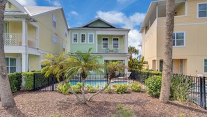 A two-story building with a pool, surrounded by palm trees and a fence. - Idyllic Waterfront Margaritaville Cottage w/ Private Pool & Spa (Kissimmee)