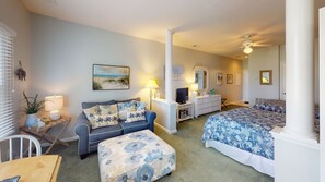 Quarto com cama, sofá, televisão e cómoda.