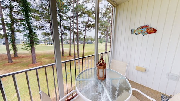 A covered outdoor area with a glass table and chairs, a lantern, and a decorative fish on the wall. - CH3509, Golf Course Escape, Your Ideal Vacation Home (Sunset Beach)