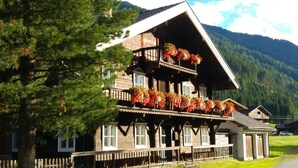 A wooden chalet with a balcony adorned with flowers, set against a mountainous backdrop. - Apartment "ERHOLUNG" for max. 7 persons (2191170) (St. Veit im Defereggental)