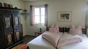 A bedroom with a wooden bed, a nightstand, a dresser, a window with curtains, and a framed picture on the wall. - Apartment "ERHOLUNG" for max. 7 persons (2191170) (St. Veit im Defereggental)