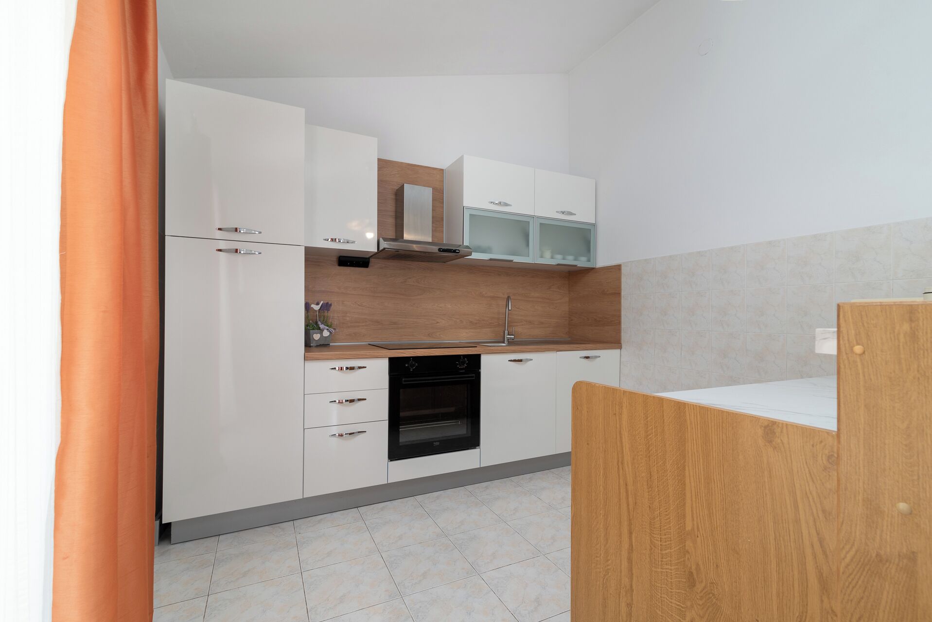 A modern kitchen with white cabinets, a wooden countertop, and a built-in oven.