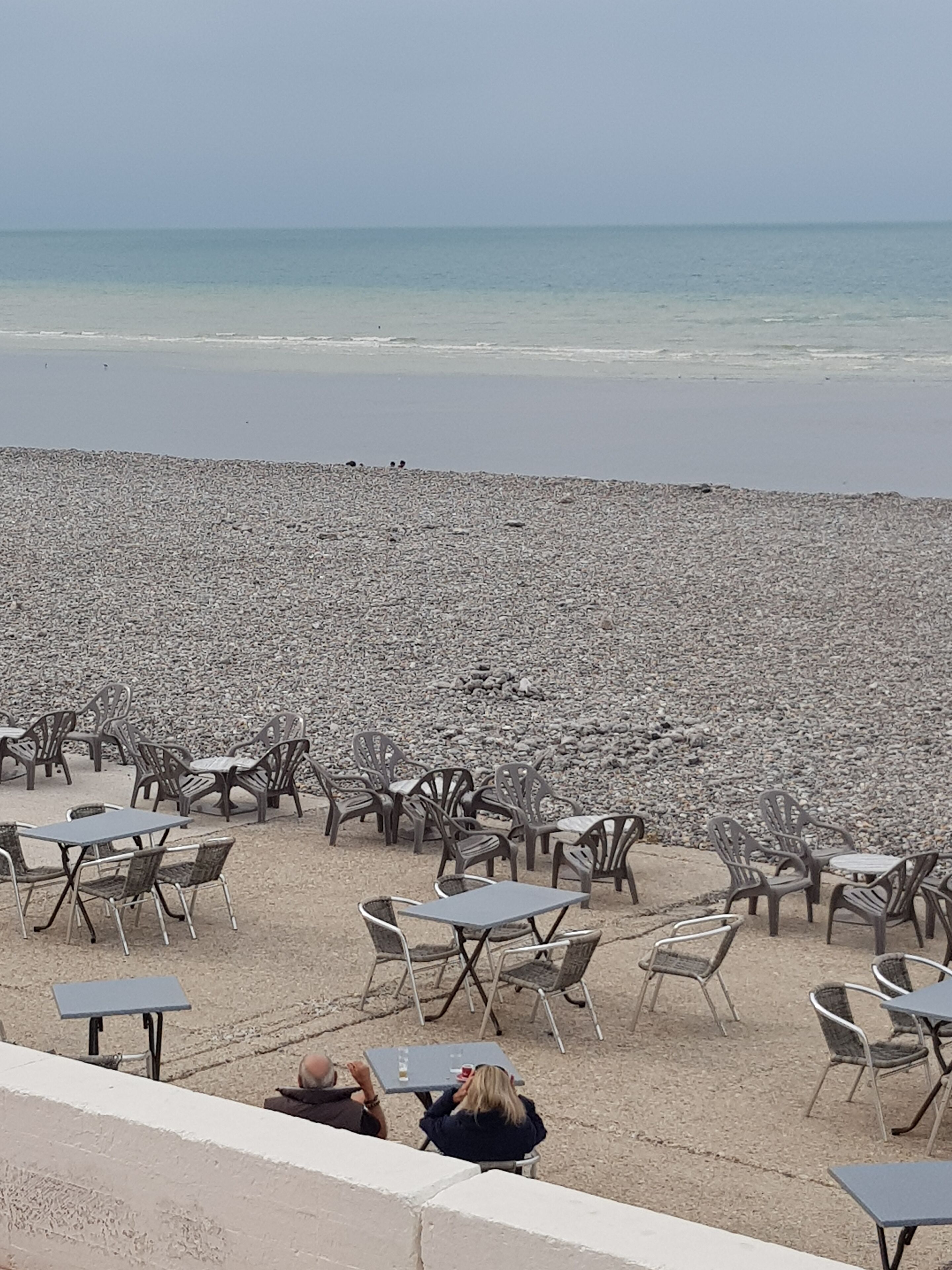 A beachside café with outdoor seating and a view of the sea.