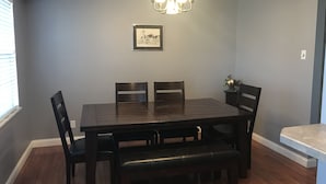 A dining room with a dark wooden table, four chairs, a bench, and a chandelier. - West County Gem - Easy access to STL attractions! (Des Peres)