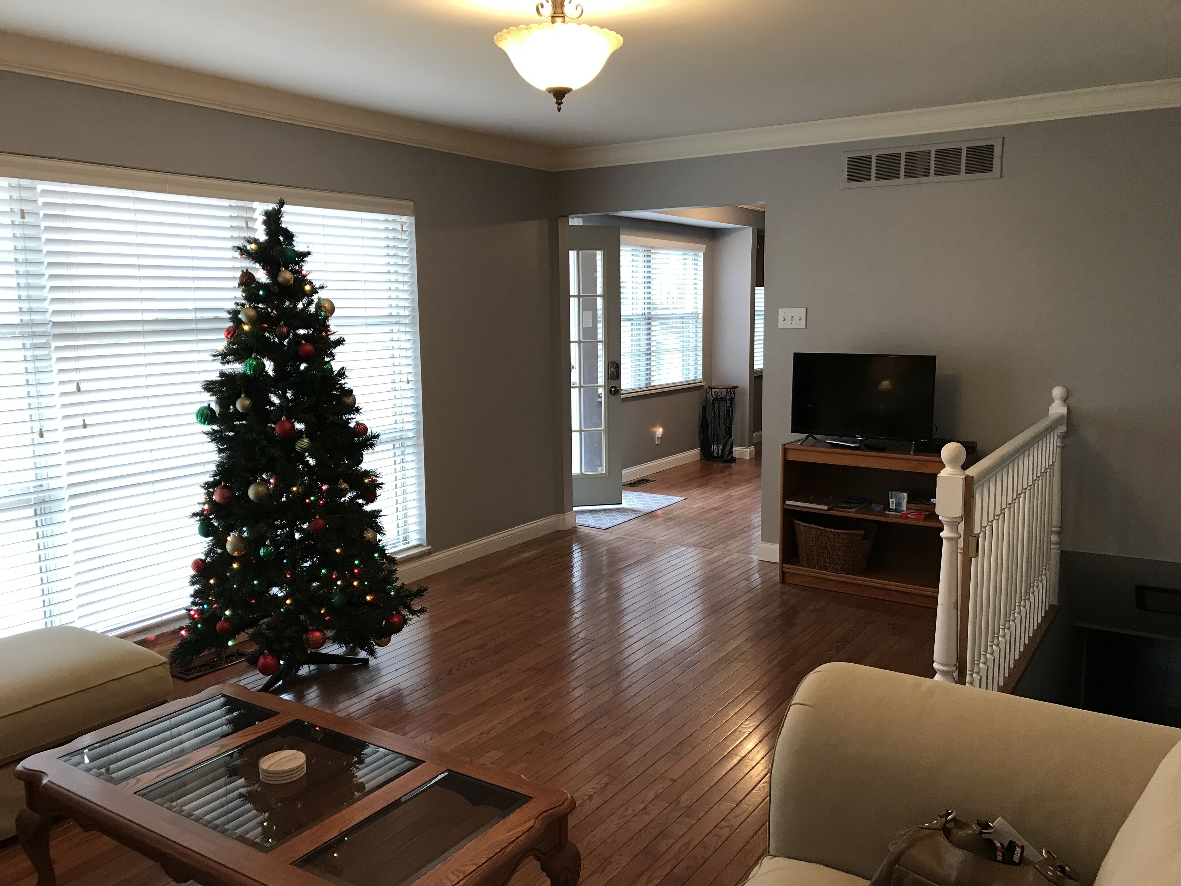 A living room with a Christmas tree, a TV on a stand, and a staircase.
