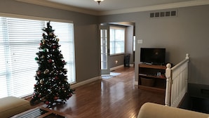 A living room with a Christmas tree, a TV on a stand, and a staircase. - West County Gem - Easy access to STL attractions! (Des Peres)