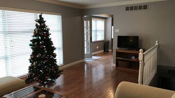A living room with a Christmas tree, a TV on a stand, and a staircase.
