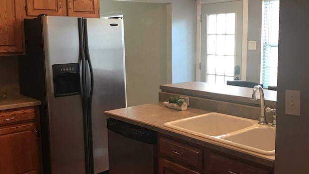 A kitchen with wooden cabinets, a stainless steel refrigerator, a dishwasher, and a double sink. - West County Gem - Easy access to STL attractions! (Des Peres)