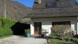 A house with a gravel driveway, a wooden door, and a small garden with potted plants. - Cottage 4 pers Laruns (Laruns)