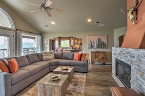 Amplia sala de estar con sofá modular, chimenea y vista a la cocina.