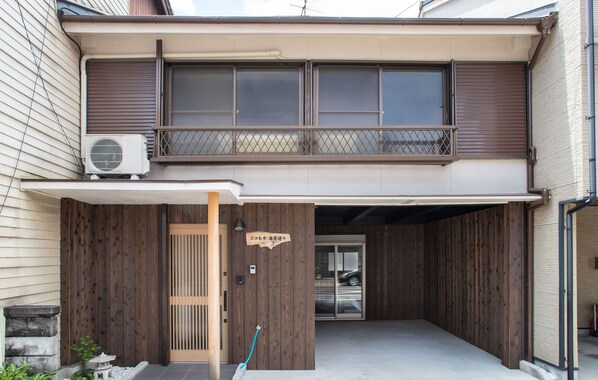 A two-story building with a covered entrance, a wooden fence, and an air conditioning unit. - Cocomosu Kaigandori (Sumoto)
