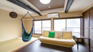 Een kamer met een bank, een hangmat en grote ramen.