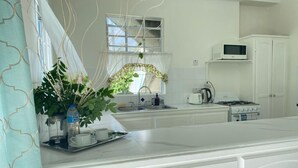 A kitchen with white cabinetry, a microwave, a stove, and a sink. - Cozy Apartments close to beach, bars and restaurants (Rodney Bay)