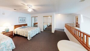 A hotel room with a bed, bedside table, lamp, mirror, and a staircase. - Golf Villa | Sunset Beach | Live the Golf Life! (CV2B) (Sunset Beach)
