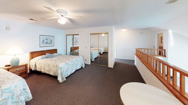 A hotel room with a bed, bedside table, lamp, mirror, and a staircase.