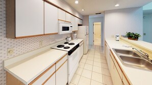 A modern kitchen with white cabinets, a stove, a microwave, and a sink. - Golf Villa | Sunset Beach | Live the Golf Life! (CV2B) (Sunset Beach)